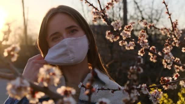 La mujer se quita la máscara médica y respira profundamente de la flor de primavera después del Coronavirus. Cierre el retrato. Movimiento lento — Vídeo de stock