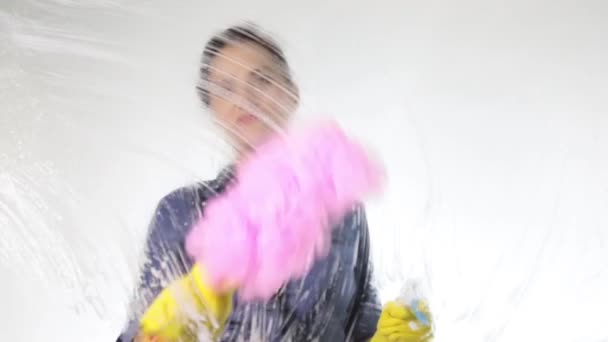 Jeune femme au foyer lavé fenêtre avec un spray, chiffon et détergent. Grand verre en mousse. Concept de travaux ménagers . — Video
