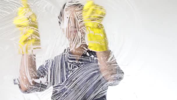 Jonge huisvrouw gewassen venster met een spray, een doek en een afwasmiddel. Grote glazen in schuim. Huishoudelijk werk concept. — Stockvideo