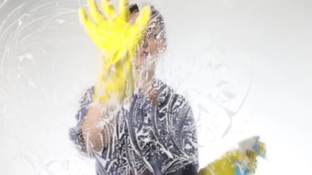 Jonge huisvrouw gewassen venster met een spray, een doek en een afwasmiddel. Grote glazen in schuim. Huishoudelijk werk concept. — Stockvideo