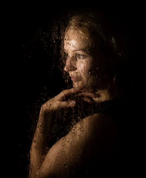 Retrato suave de modelo sexy, posando detrás de vidrio transparente cubierto por gotas de agua . — Foto de Stock