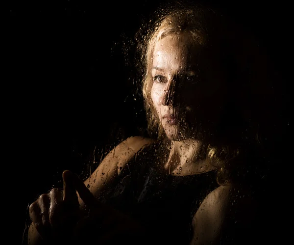 Retrato liso de modelo sexy, posando detrás de vidrio transparente cubierto por gotas de agua. joven melancolía y triste mujer retrato — Foto de Stock