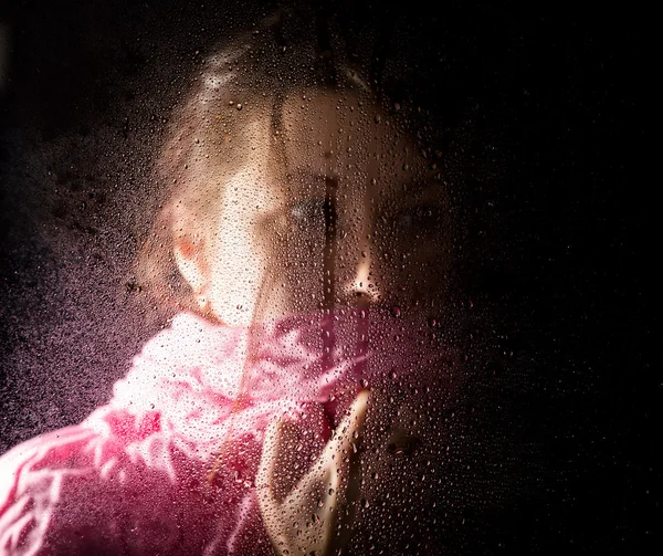 Joven mujer triste retrato detrás de la ventana en la lluvia con gotas de lluvia sobre ella — Foto de Stock