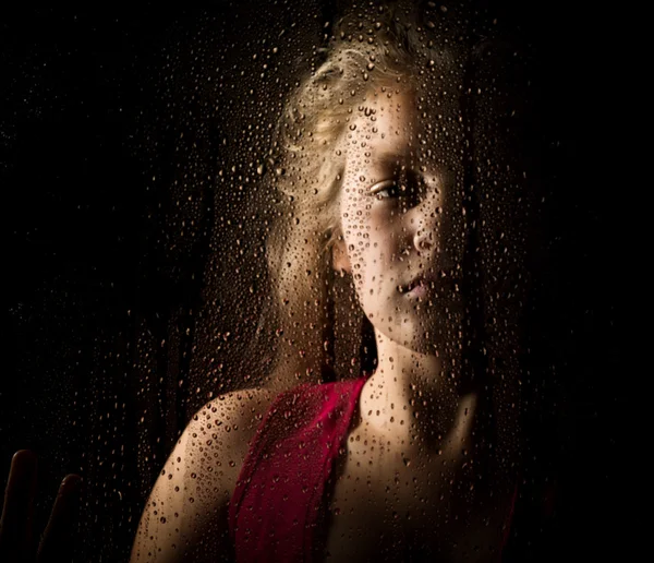 Lonely young sad girl behind the window with drops — Stock Photo, Image