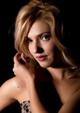 Güzel kıvırma saçları ve profesyonel makyaj ile genç bir sarışın kadının portresi. koyu bir arka plan üzerinde