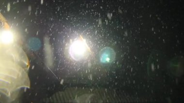 siyah bir arka plan ve parlak lamba üzerinde gökyüzünden düşen birçok kar gevreği. kar ve ışık yansımaları