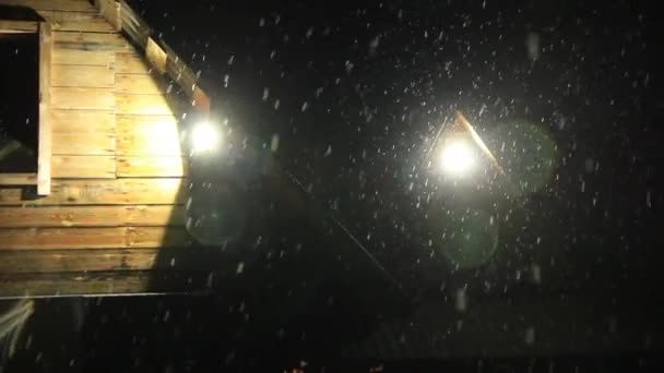 Viele Schneeflocken fallen vom Himmel auf schwarzem Hintergrund und heller Lampe. Schnee und Lichtreflexionen — Stockvideo
