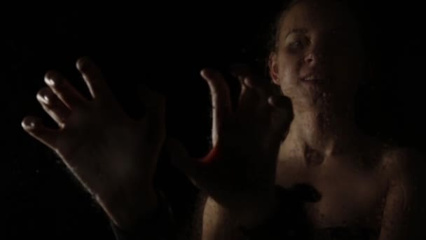 Bella donna nuda mostra le mani con le manette su sfondo nero. Ragazza dietro il bicchiere e gocce d'acqua su di esso. Concetto BDSM — Video Stock