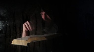 Necromancer mum, şeffaf cam su damlaları karanlık bir arka plan üzerinde kapsadığı arkasında kalın antik kitaptan büyü atmalarını