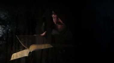 Necromancer mum, şeffaf cam su damlaları karanlık bir arka plan üzerinde kapsadığı arkasında kalın antik kitaptan büyü atmalarını