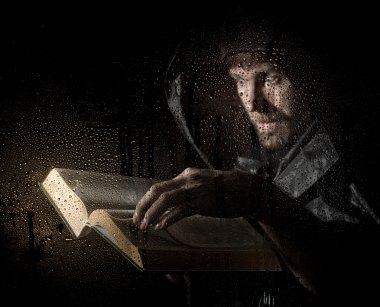 necromancer casts spells from thick ancient book, behind transparent glass covered by water drops on a dark background clipart