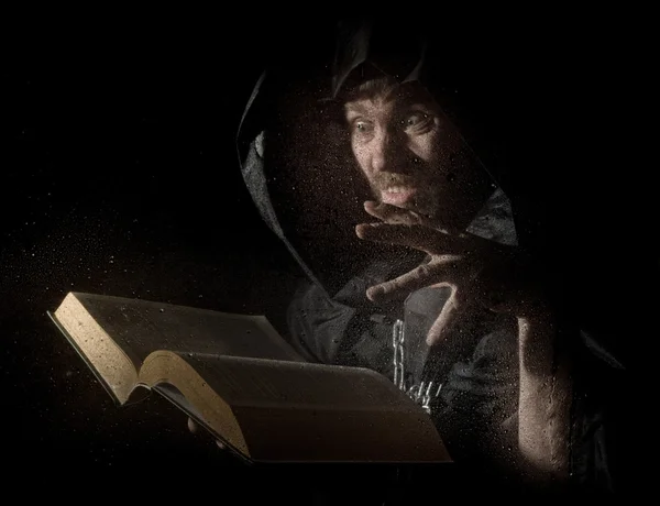 necromancer casts spells from thick ancient book, behind transparent glass covered by water drops on a dark background