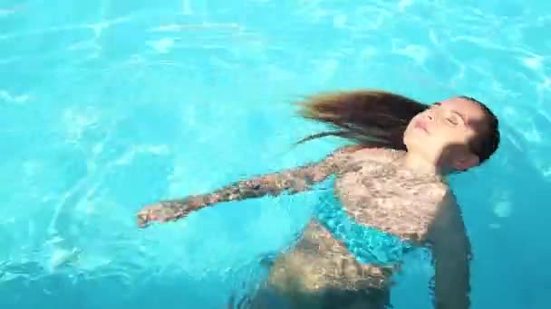 Jovem mulher feliz nadando e gira em uma piscina — Vídeo de Stock