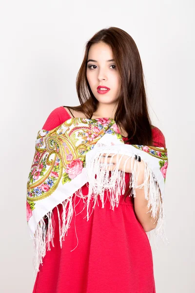 Schöne junge Frau in rotem Kleid und farbigem Schal posiert im Studio — Stockfoto