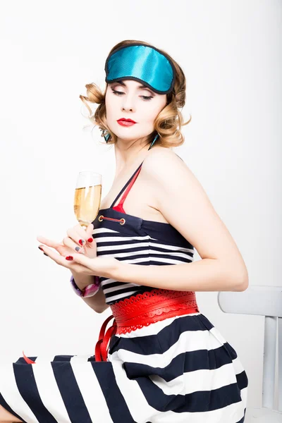 Vacker ung kvinna i en randig klänning som håller ett glas champagne — Stockfoto