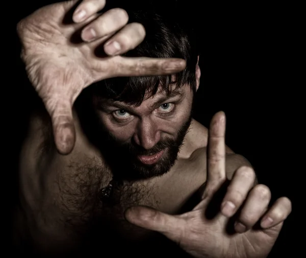 Dark portrait of scary evil sinister bearded man with smirk, making signs with your fingers. strange Russian man with a naked torso — Stock fotografie