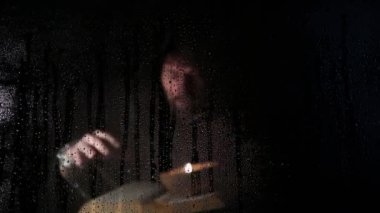Necromancer mum, şeffaf cam su damlaları karanlık bir arka plan üzerinde kapsadığı arkasında kalın antik kitaptan büyü atmalarını
