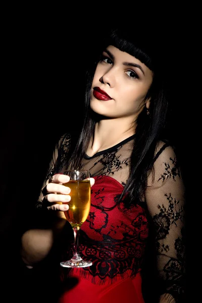 Giovane donna celebrante in un abito rosso con in mano un bicchiere di champagne — Foto Stock