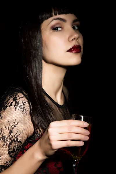 Young celebrating woman in a red dress holding a glass of champagne — Stockfoto