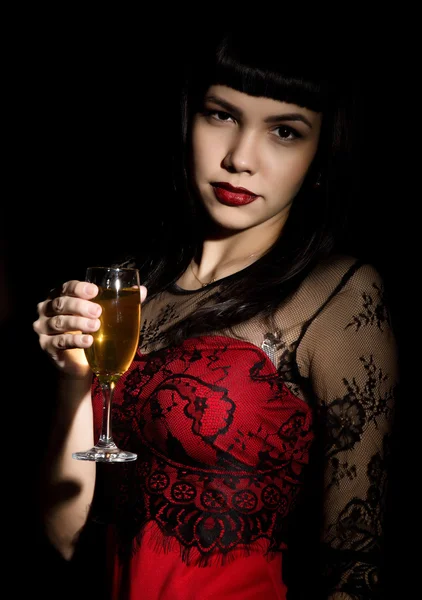 Young celebrating woman in a red dress holding a glass of champagne — Stockfoto