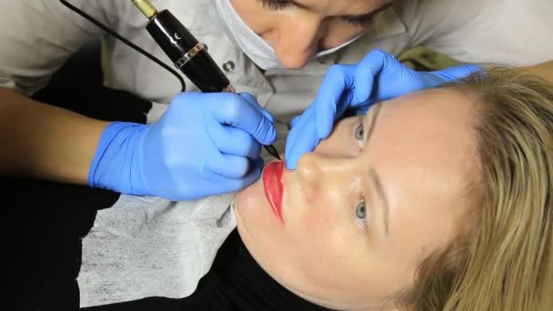 Kosmetikerin, die Permanent Make-up aufträgt. junge schöne Frau mit kosmetischen Tätowierungen auf den Lippen. Gesunder Kurort — Stockvideo