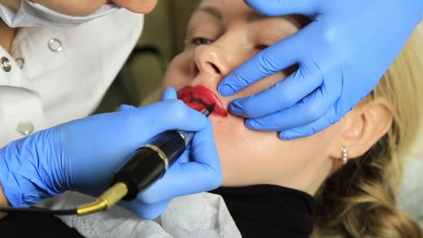 Cosmetólogo aplicando maquillaje permanente. Joven hermosa mujer con tatuaje cosmético en los labios. Spa saludable — Vídeos de Stock