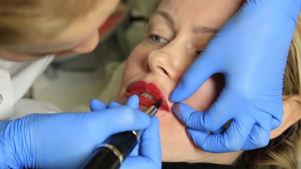 Kosmetikerin, die Permanent Make-up aufträgt. junge schöne Frau mit kosmetischen Tätowierungen auf den Lippen. Gesunder Kurort — Stockvideo
