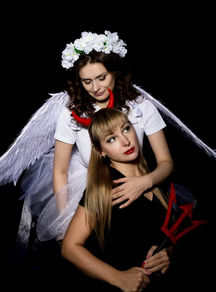 Portrait of angel and devil womans on a dark background