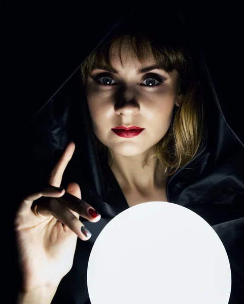 mysterious young woman wonders on a large luminous ball. on a dark background