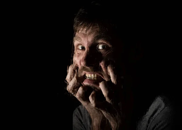 Portrait sombre de l'homme barbu effrayant avec le sourire, exprime différentes émotions. Des gouttes d'eau sur un verre, une main et un visage masculin — Photo