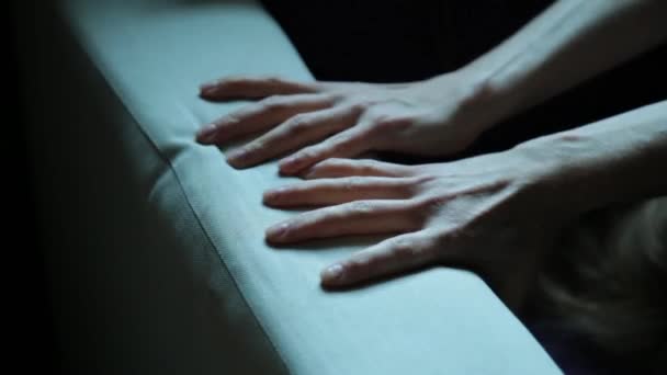 Close-up van de handen van een jonge vrouw liggend op een slechte. Meisje verfrommelt bekleding Bank — Stockvideo