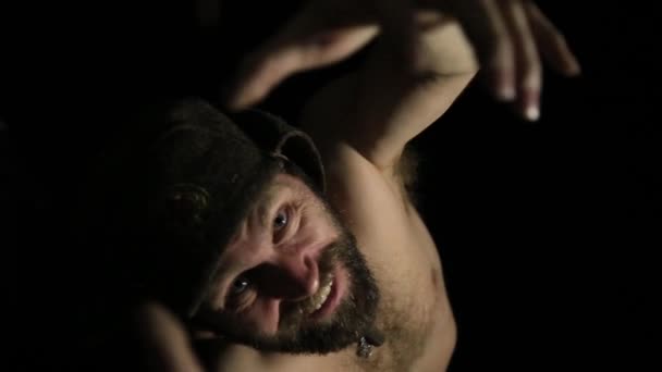 Gruselig böser finsterer bärtiger Mann mit einem Lächeln, der nach der Kamera greift. seltsamer russischer Mann mit nacktem Oberkörper und Wollmütze — Stockvideo