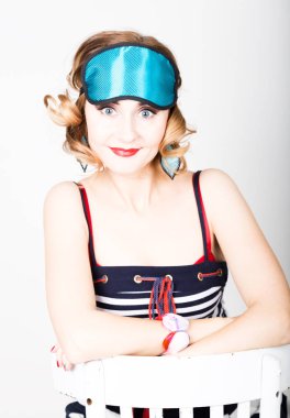 çizgili elbise ve uyku, bir sandalyede oturuyor ve poz için puan güzel ve genç birbayan. uyku göz maskesi kapsayan