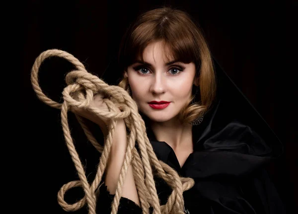 Таинственная молодая женщина держит петлю на веревке. на темном фоне — стоковое фото