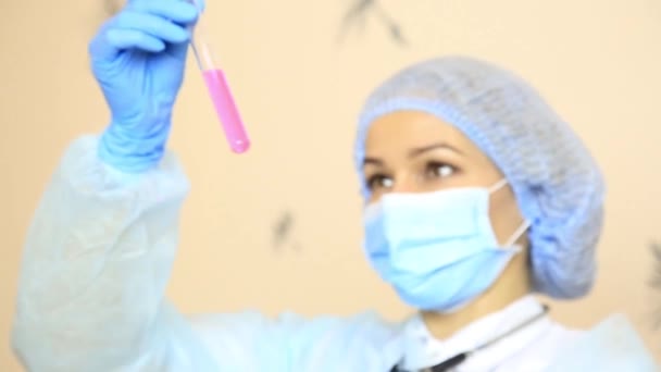 Médico fêmea de uniforme médico segurando um tubo de ensaio — Vídeo de Stock