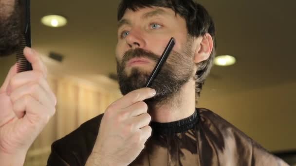 Közeli fiatal jóképű férfi tisztítás szakáll ollóval. Fiatal ember dolgozik a szakállát, és fésű, olló stílus szépségszalon. — Stock videók