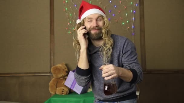 Evil dwarf or bad santa talking on a phone and drinking brandy from a bottle — Stock Video