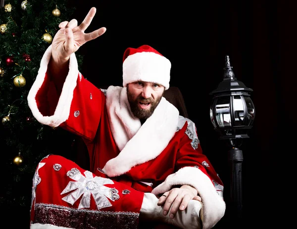 Bad rastoman Santa Claus doing different finger signs on the background of Christmas tree — Stock Photo, Image