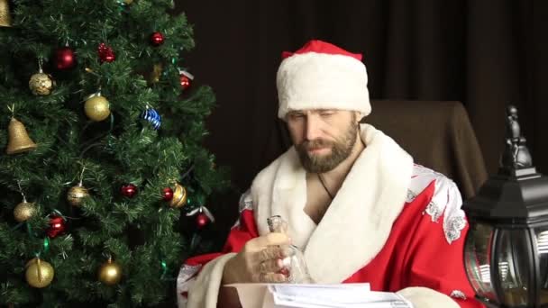 Mal brutal Santa Claus descontento lee carta con los deseos, en el fondo del árbol de Navidad — Vídeo de stock