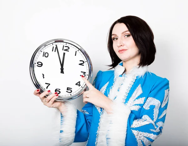 Mujer en uniforme de navidad sosteniendo un reloj, apuntando hacia la derecha — Foto de Stock