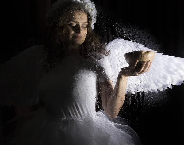 Retrato de ángel y diablo sobre un fondo oscuro, detrás de vidrio transparente cubierto por gotas de agua . — Foto de Stock