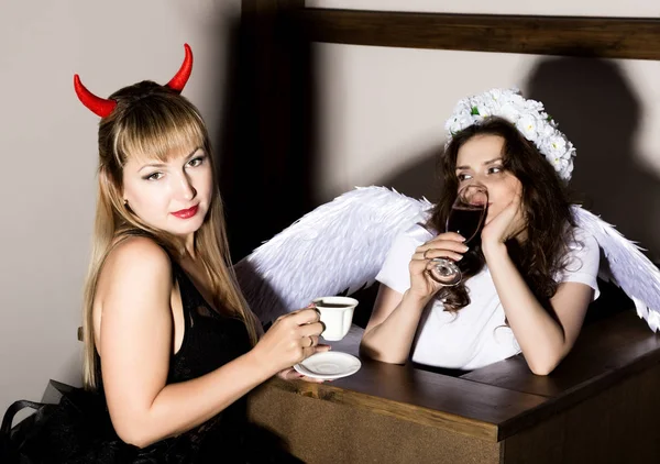 Portrét anděl a ďábel Zenske pít kávu nad víno — Stock fotografie