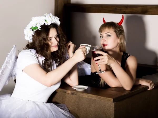 Portrait of angel and devil womans drink coffee nad wine
