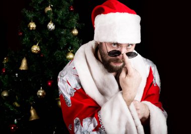kötü rastoman Noel Baba Noel ağacı arka plan üzerinde yuvarlak gözlük ve gülümsüyor, tutar. farklı funy duygular