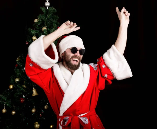 Mala rastomía Santa Claus sonrisas y diversión bailando en el fondo del árbol de Navidad —  Fotos de Stock