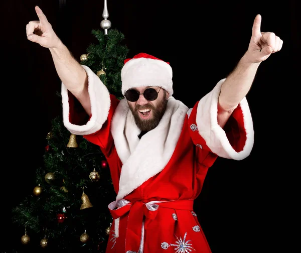 Mauvais rastoman Père Noël sourit et danse amusante sur le fond de l'arbre de Noël — Photo