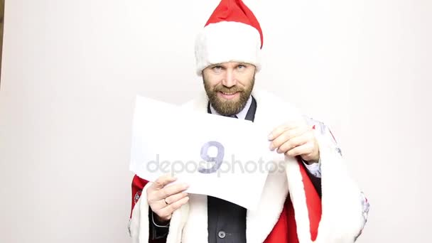 Geschäftsmann im Weihnachtsmannanzug hält ein Blatt Papier mit Zahlen in der Hand. Endgültiger Countdown — Stockvideo