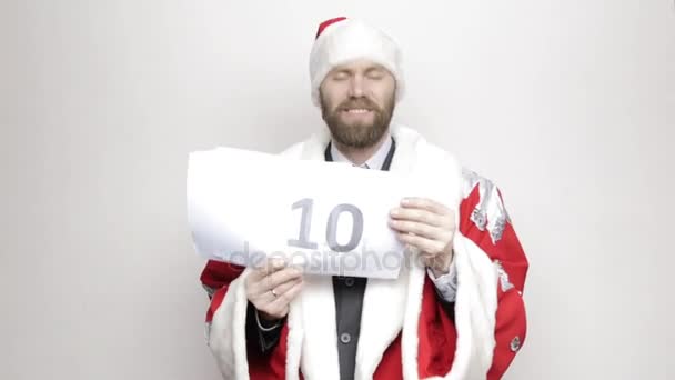Geschäftsmann im Weihnachtsmannanzug hält ein Blatt Papier mit Zahlen in der Hand. Endgültiger Countdown — Stockvideo