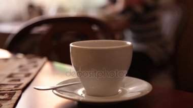Çay veya kahve içme ve gülümseyen kafede oturan genç ve güzel kadın