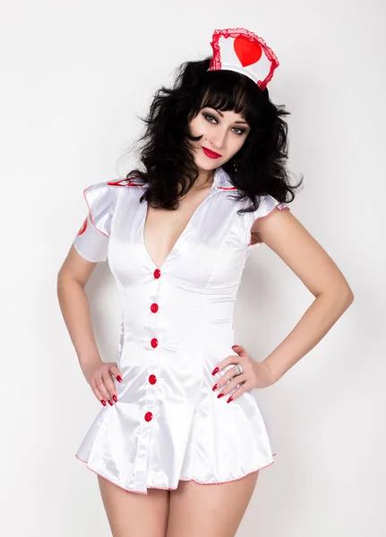 Joven hermosa mujer vestida como enfermera, traje de carnaval médico, ella sosteniendo un estetoscopio y jeringa — Foto de Stock